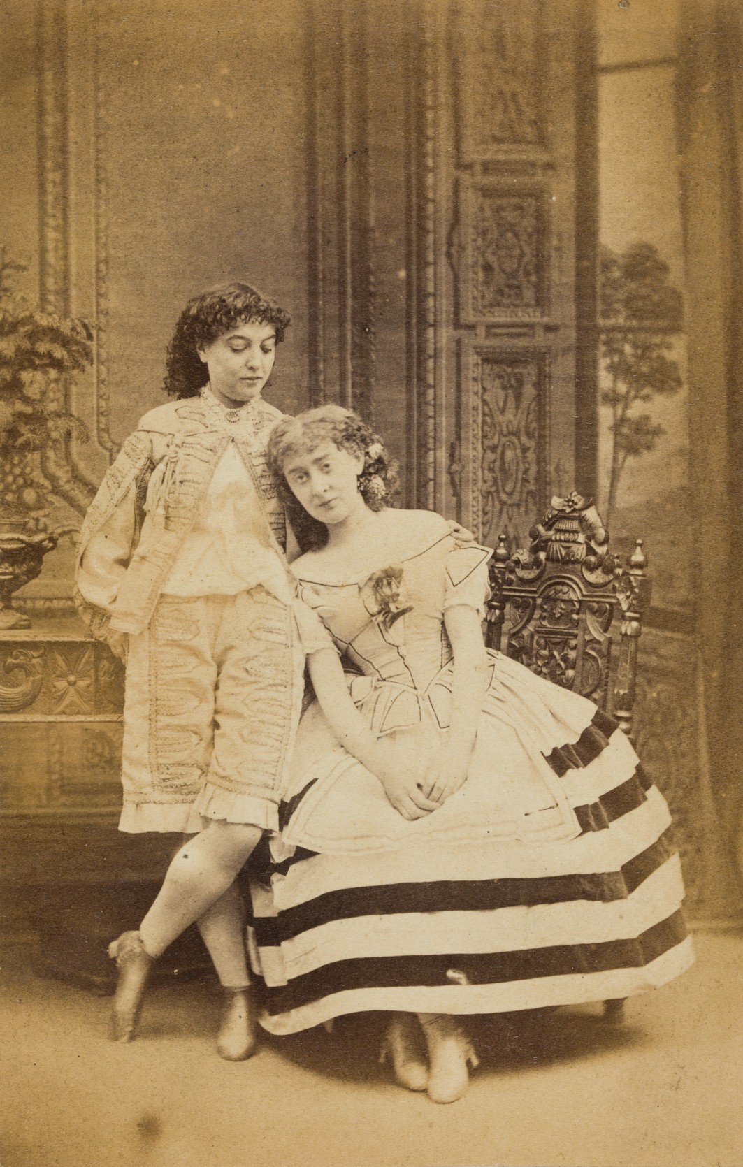 19th century image of two women, one standing and one seated
